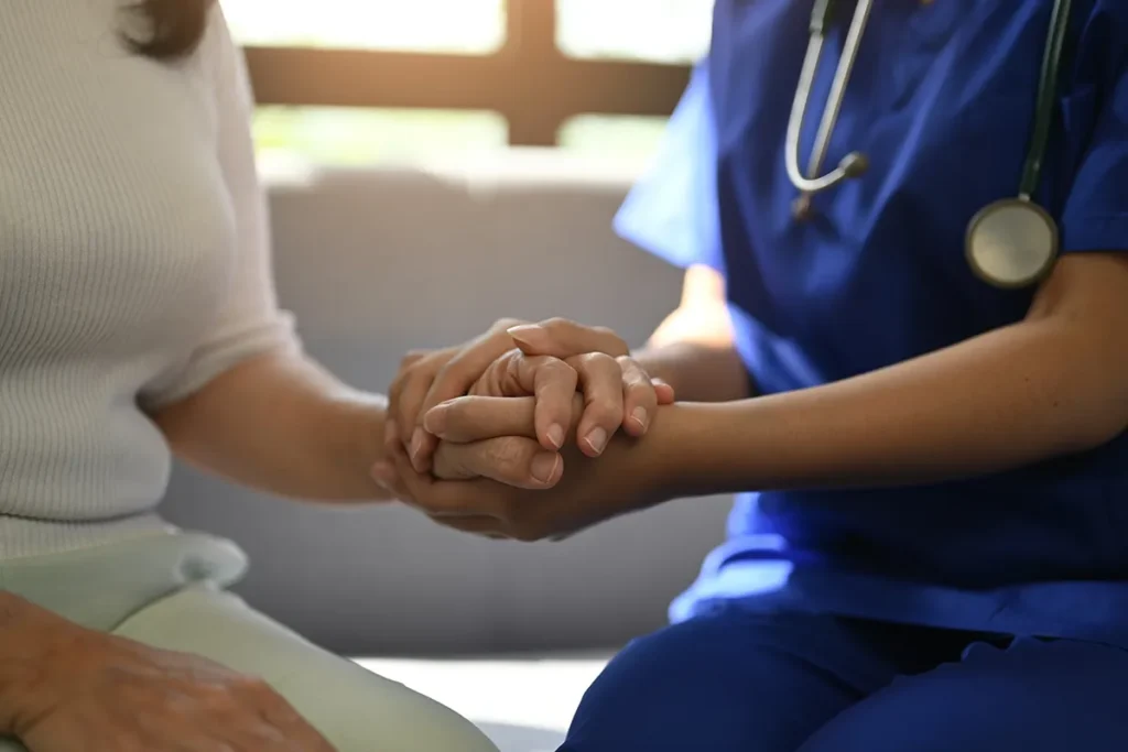caring-nurse-holding-senior-woman-s-hand-indoors